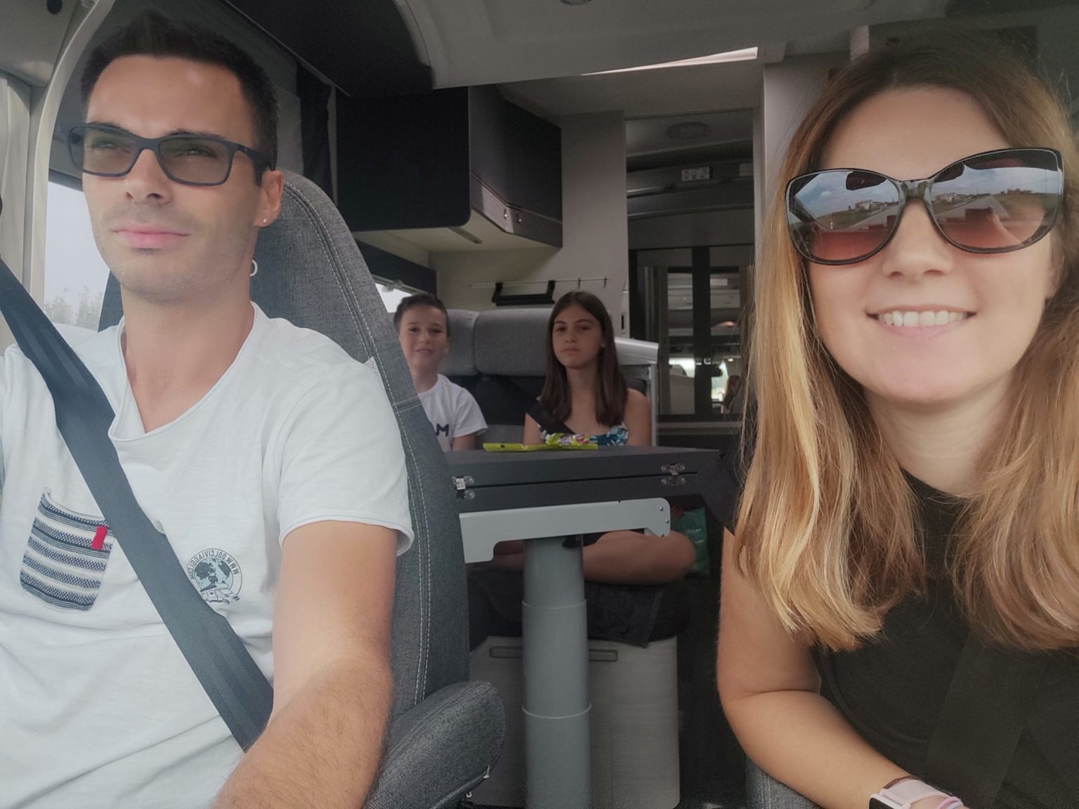 Famille souriante en voyage en camping-car, ambiance détendue et conviviale, idéale pour les aventures en plein air.