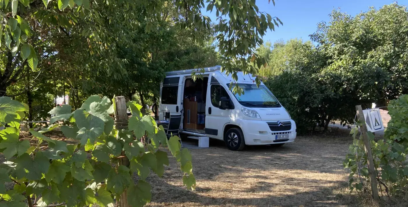 Un fourgon aménagé stationné sur un emplacement ombragé