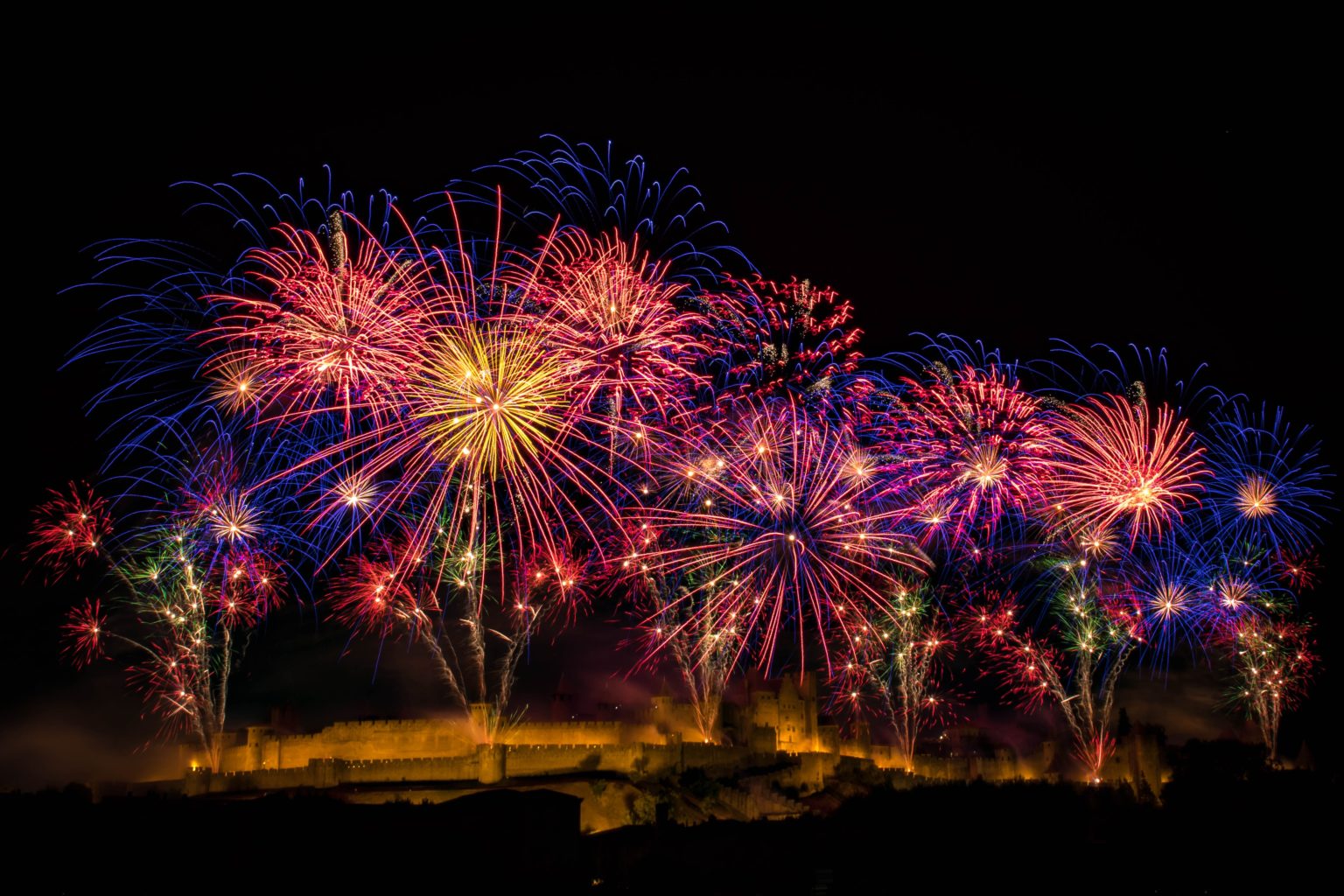 Feu d'artifice éclatant au-dessus d'un château illuminé, créant une ambiance festive et magique.