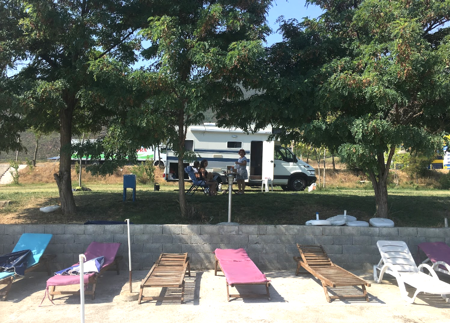 Camping ombragé avec transats et camping-cars en Albanie.