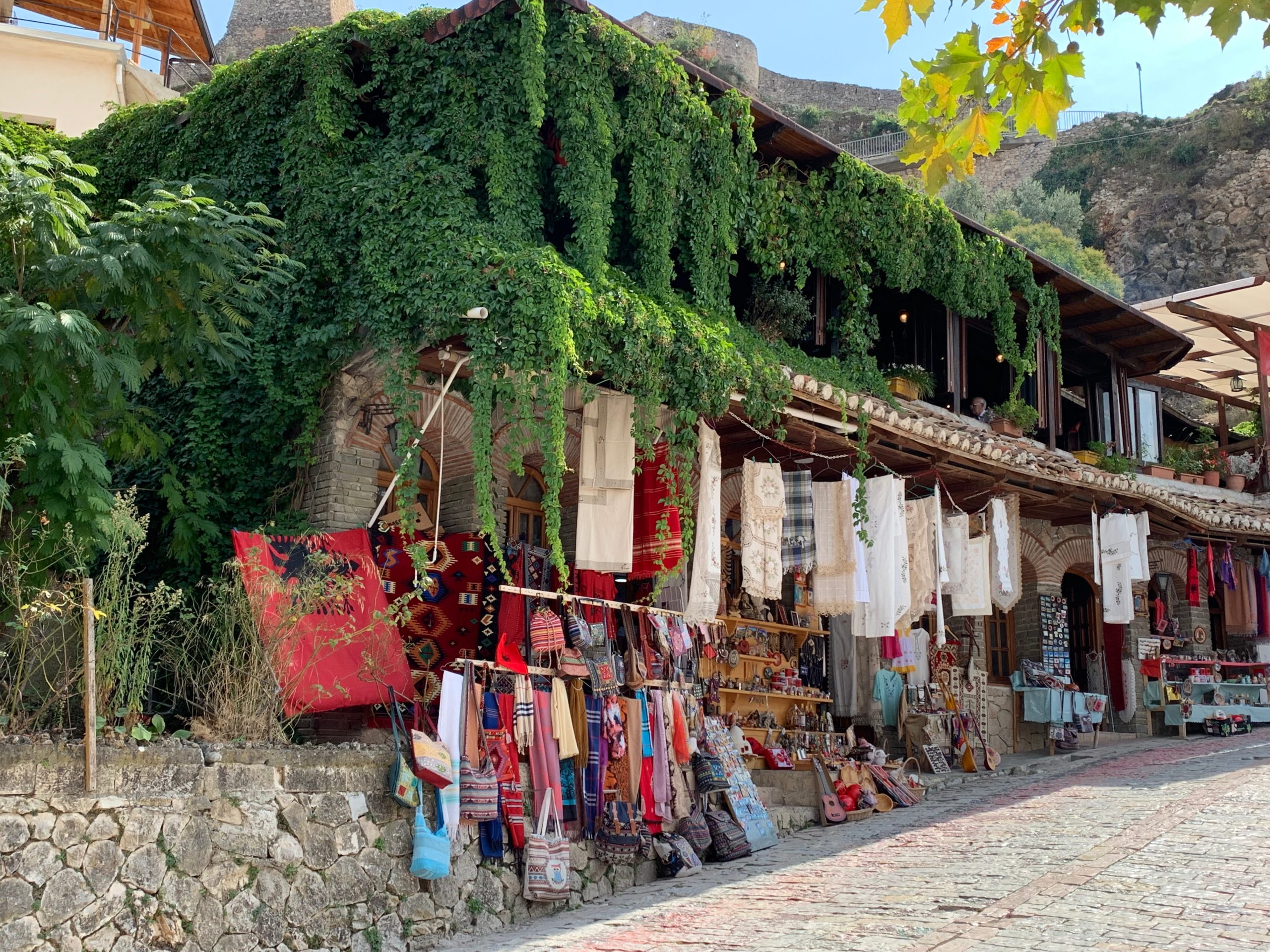 Rue traditionnelle de Gjirokastër avec boutiques artisanales en Albanie.