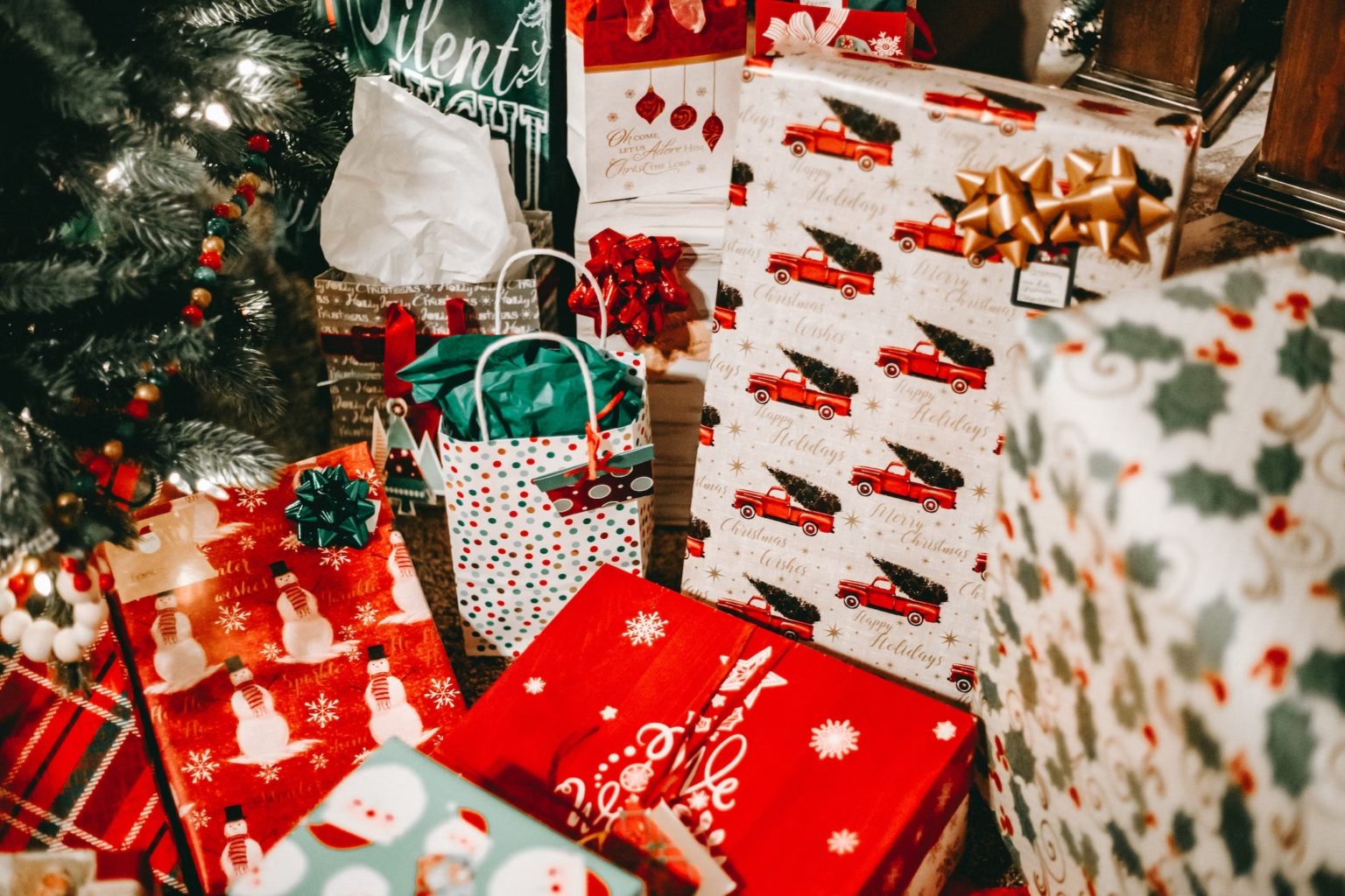 Festive Christmas gifts under a decorated tree, featuring campervan-themed wrapping paper and holiday cheer.