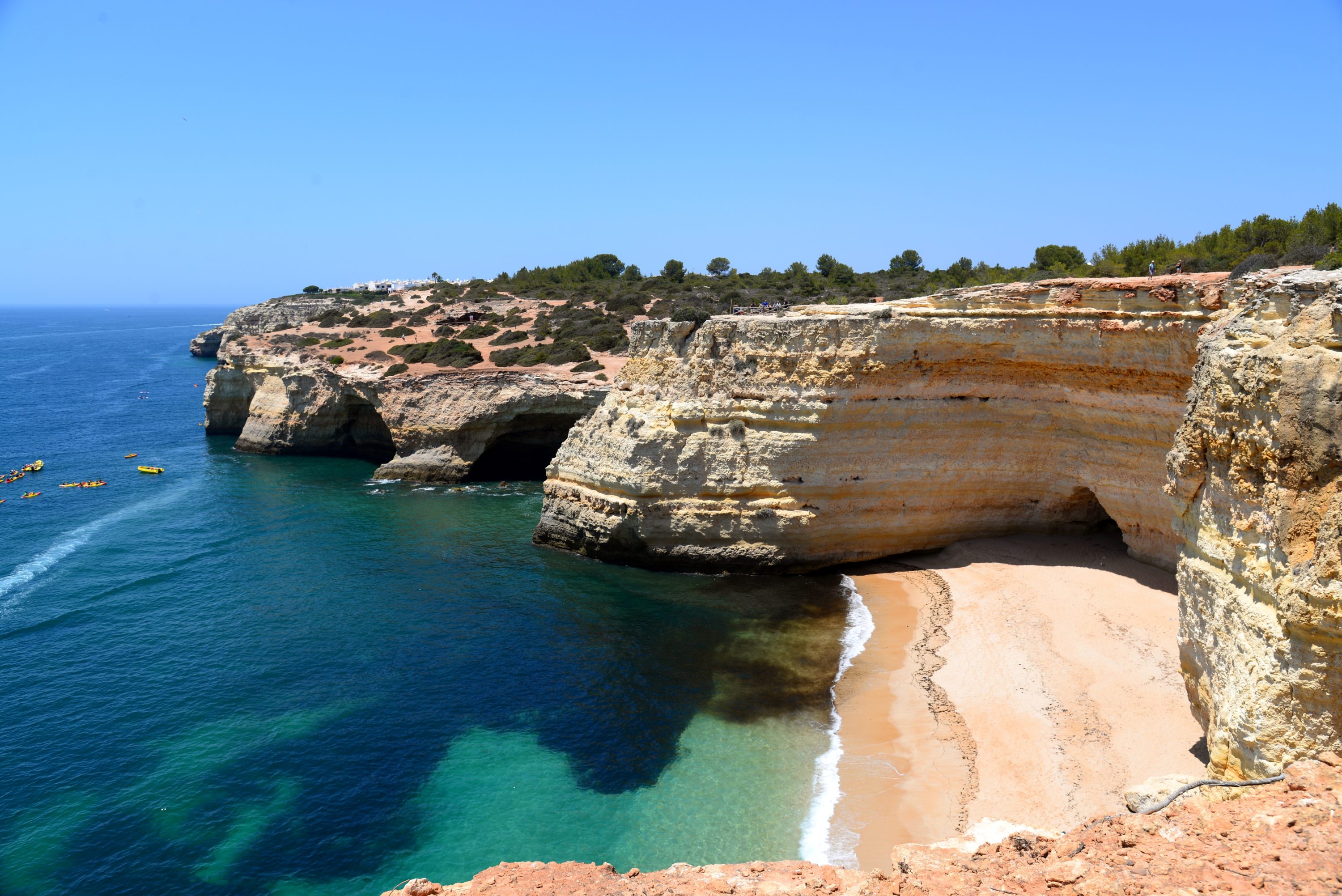Falaises majestueuses surplombant une plage isolée au bord d'une mer turquoise, ambiance estivale et sereine.