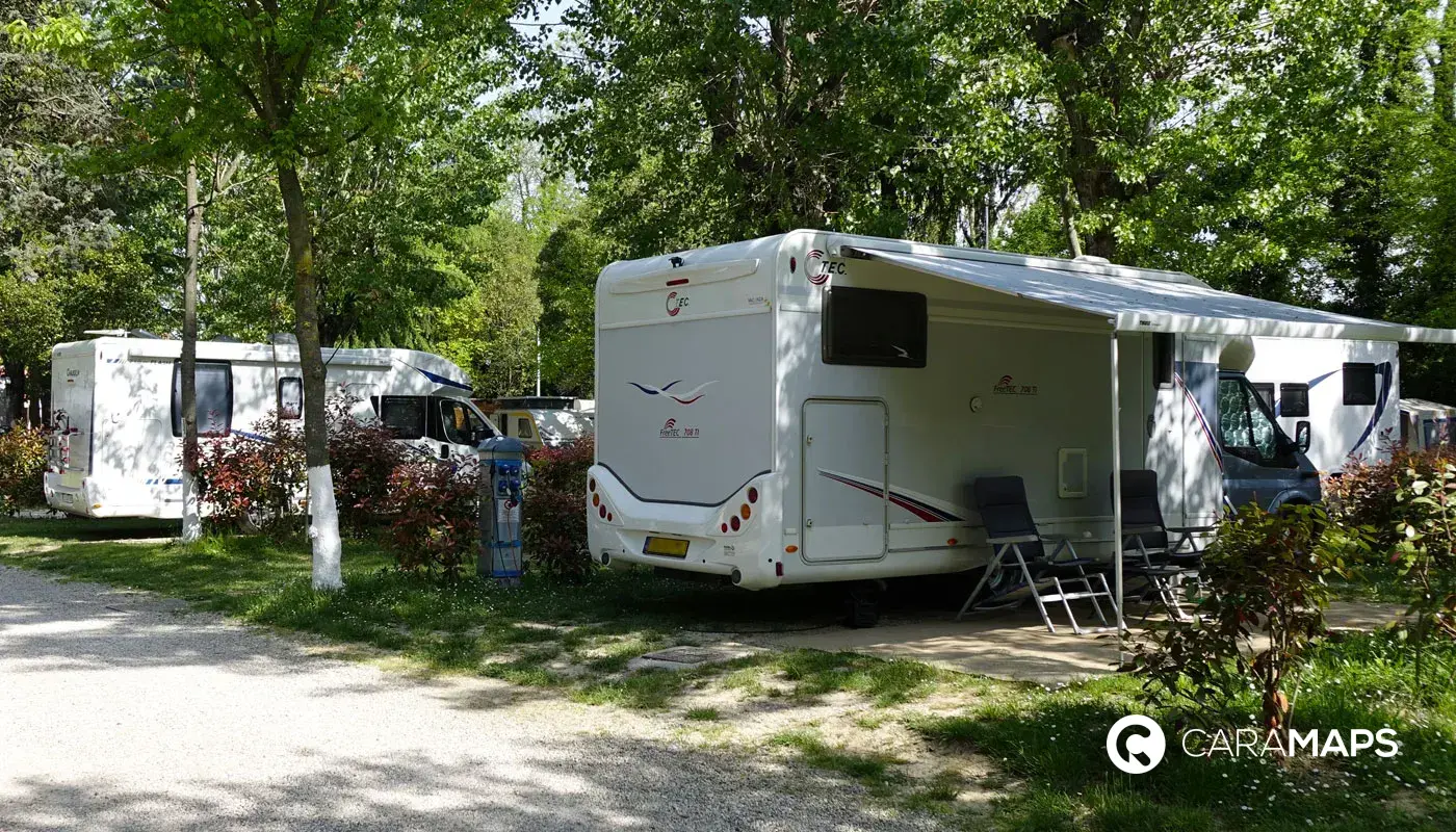 Camping-car stationné au Camping Rialto Village, entouré d’arbres et d’emplacements ombragés près de Venise.