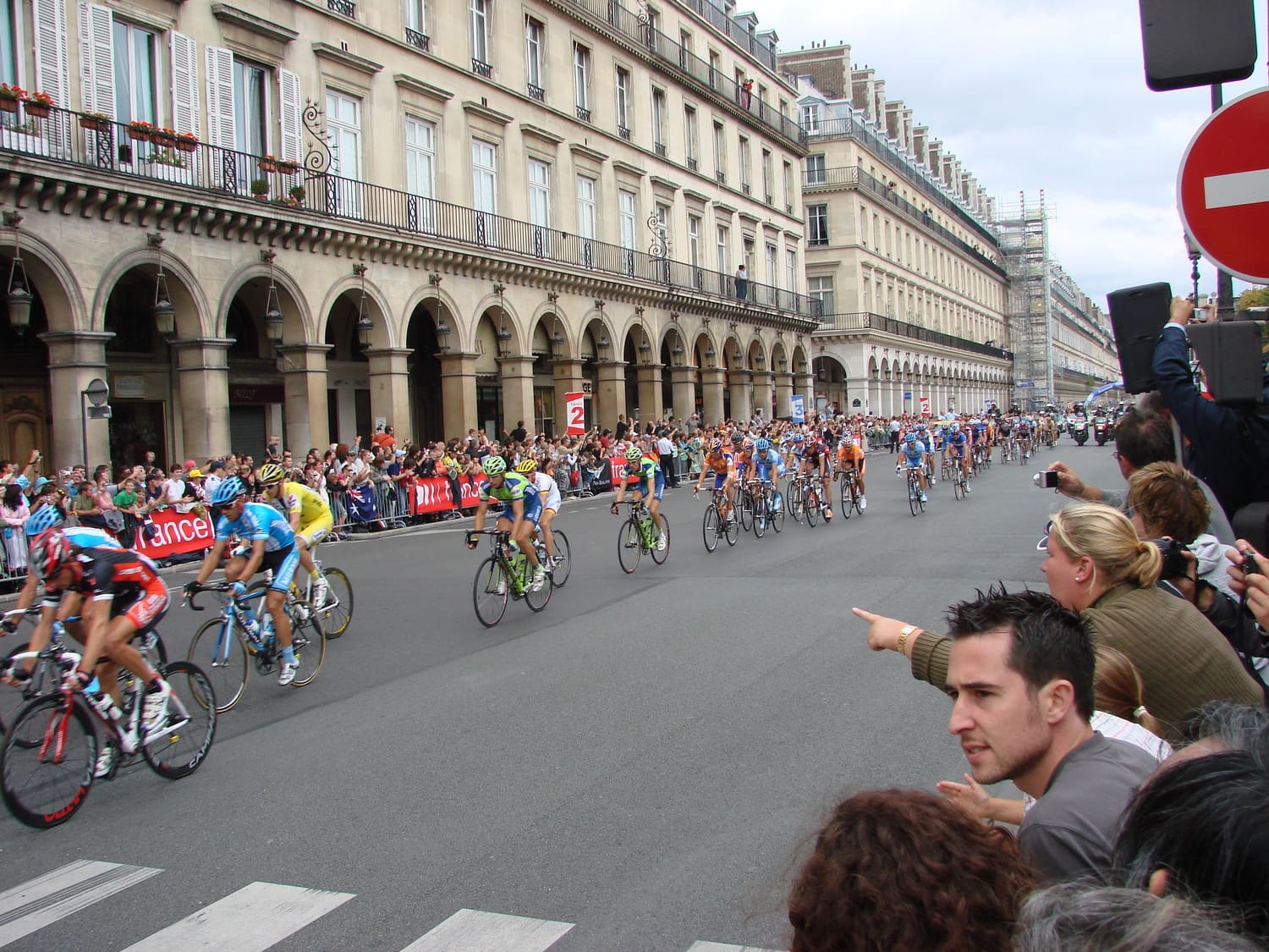 Coureurs du Tour de France sur les Champs-Élysées à Paris devant une foule de spectateurs.