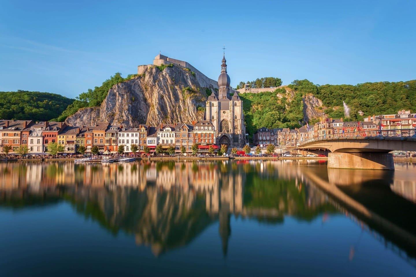 Vue de Dinant avec la collégiale Notre-Dame, la citadelle et leurs reflets sur la Meuse.