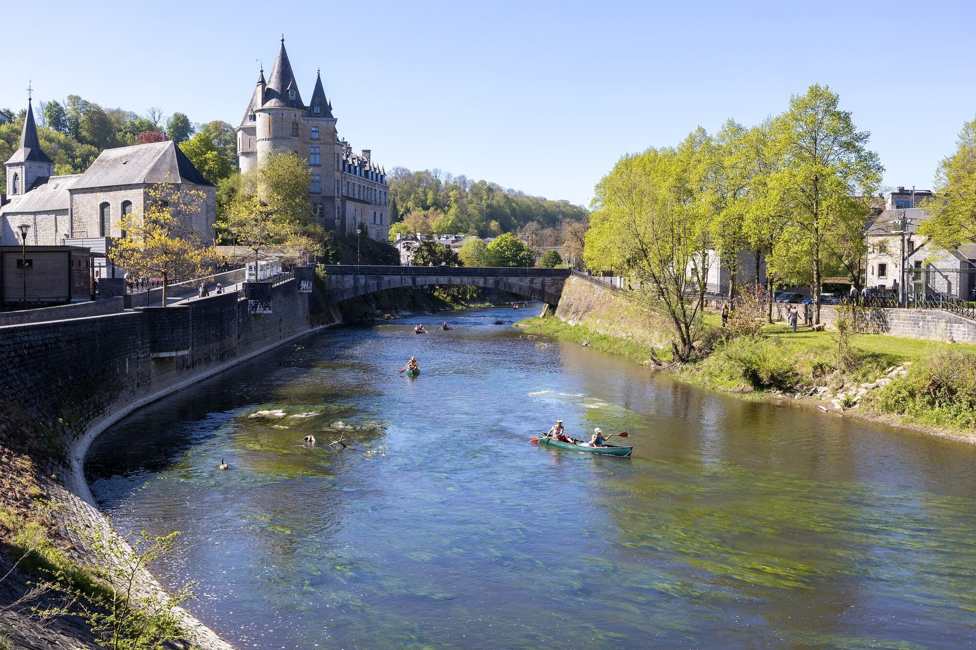 Vue de Durbuy et du château dominant l’Ourthe, avec des kayakistes sur la rivière.