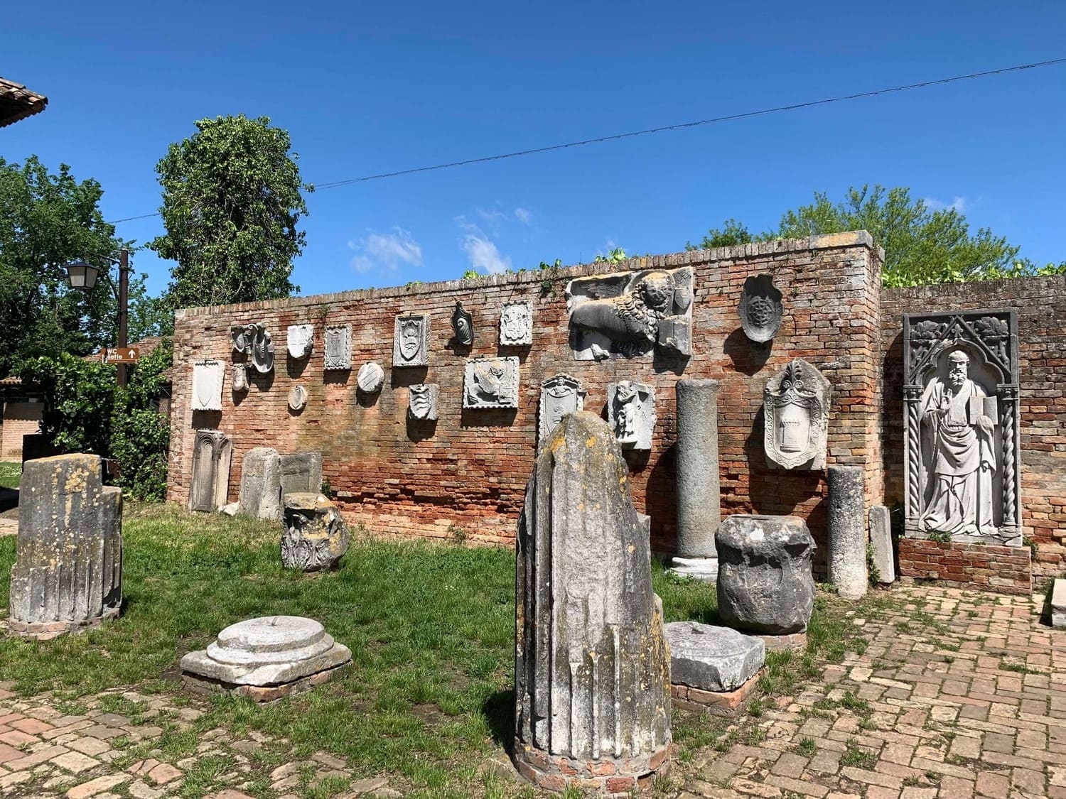Mur ancien du musée de Torcello en Italie avec sculptures en pierre et vestiges de colonnes historiques sur l’île de Torcello près de Venise.