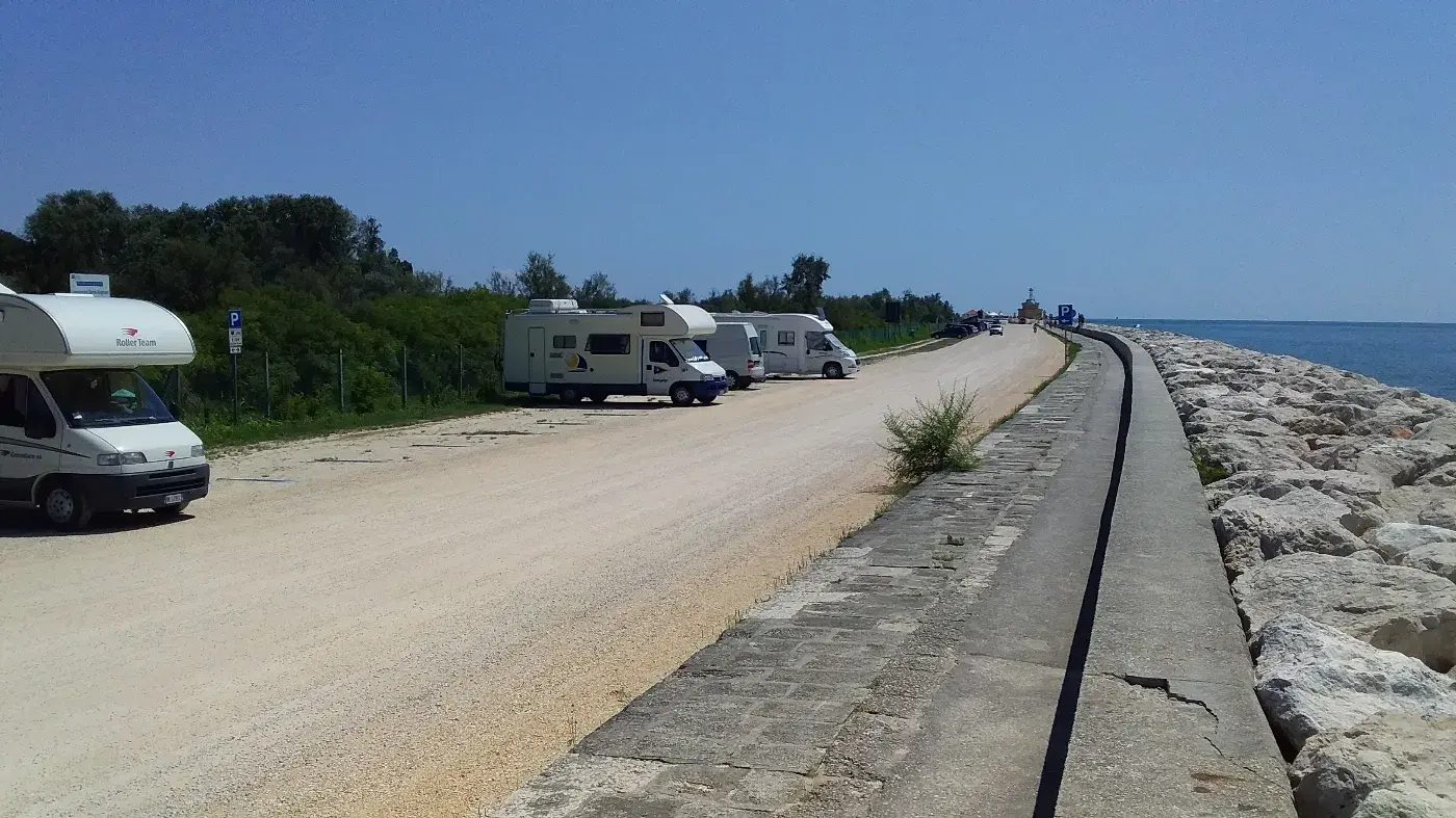 Camping-cars stationnés près de la mer sur une route côtière ensoleillée, ambiance paisible.