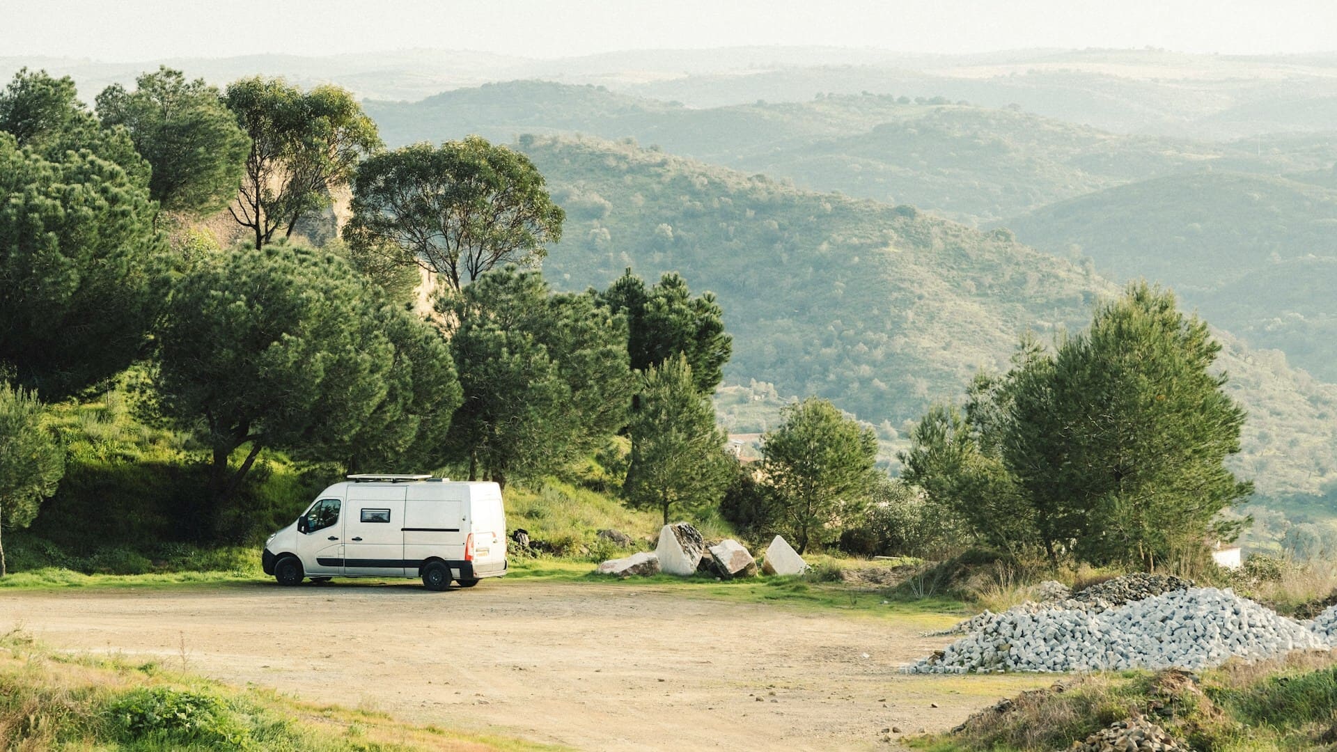 Photo d'un camping-car garé en montagne entre forêts. Montagnes sur l'horizon.