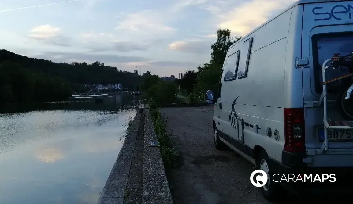 Camping-car stationné au bord de l’eau dans les Ardennes belges au coucher du soleil.