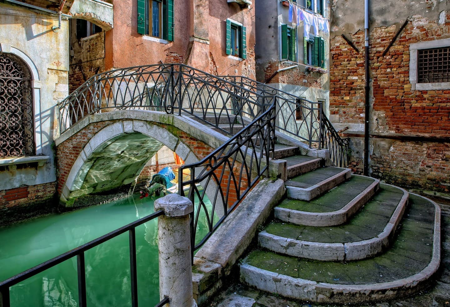 Petit pont en pierre au-dessus d’un canal étroit dans une ruelle typique de Venise.