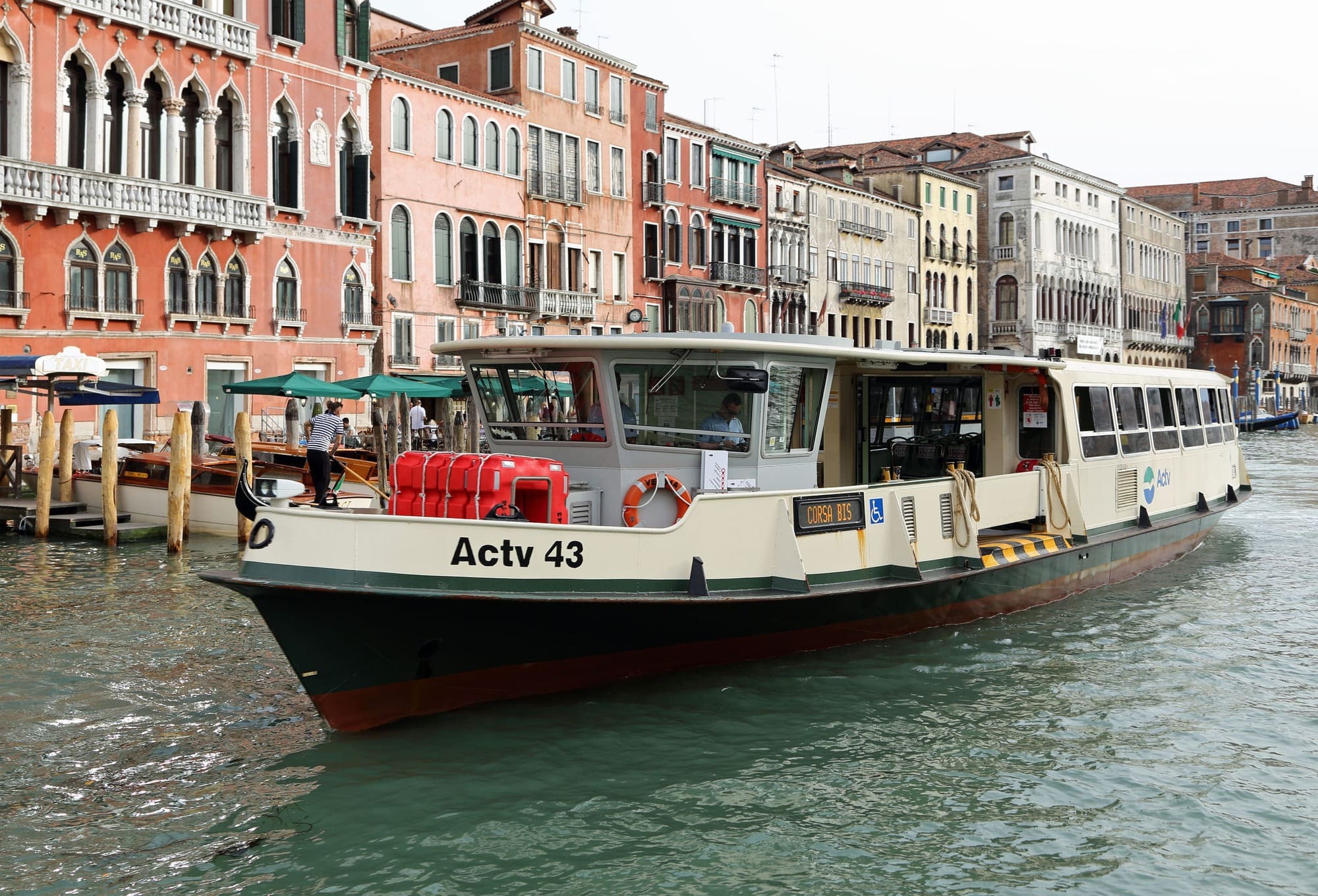 Vaporetto naviguant sur le Grand Canal à Venise, entouré de bâtiments colorés, ambiance paisible et touristique.