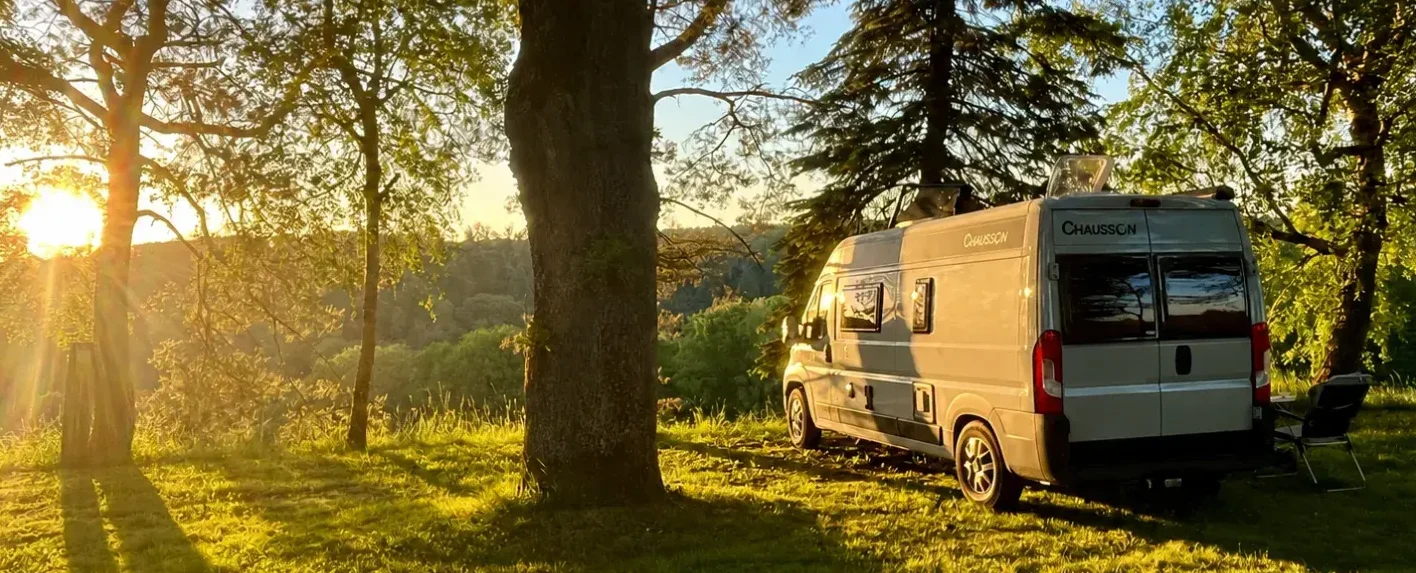 Fourgon aménagé stationné dans une forêt au coucher du soleil, réglementation du stationnement 2026