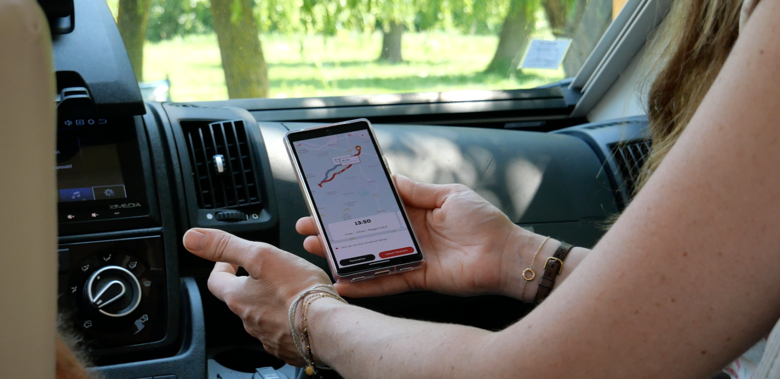 A person holding a phone that uses the GPS feature of the CaraMaps app, with CaraMaps open on the phone