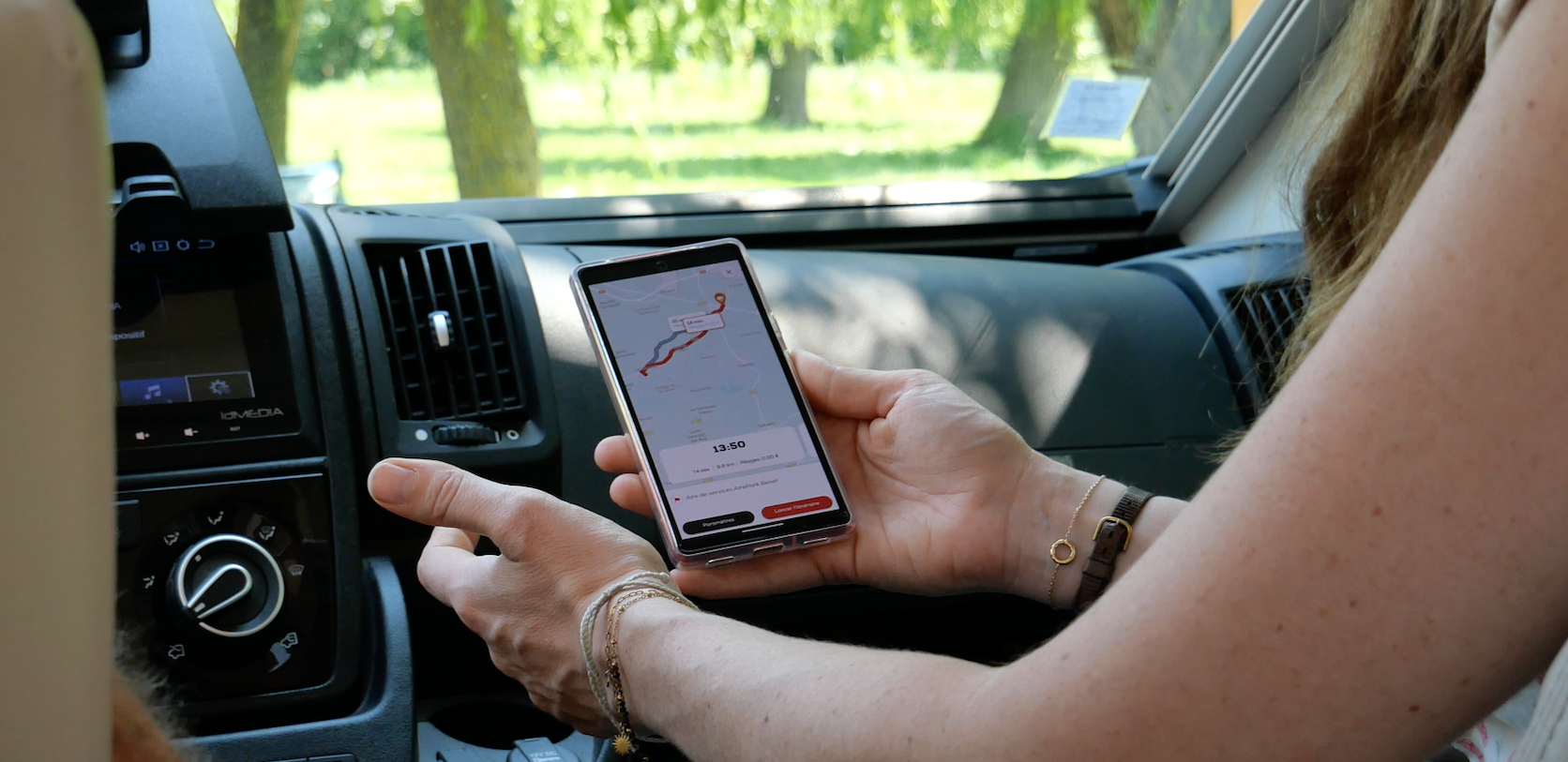 A person holding a phone that uses the GPS feature of the CaraMaps app, with CaraMaps open on the phone